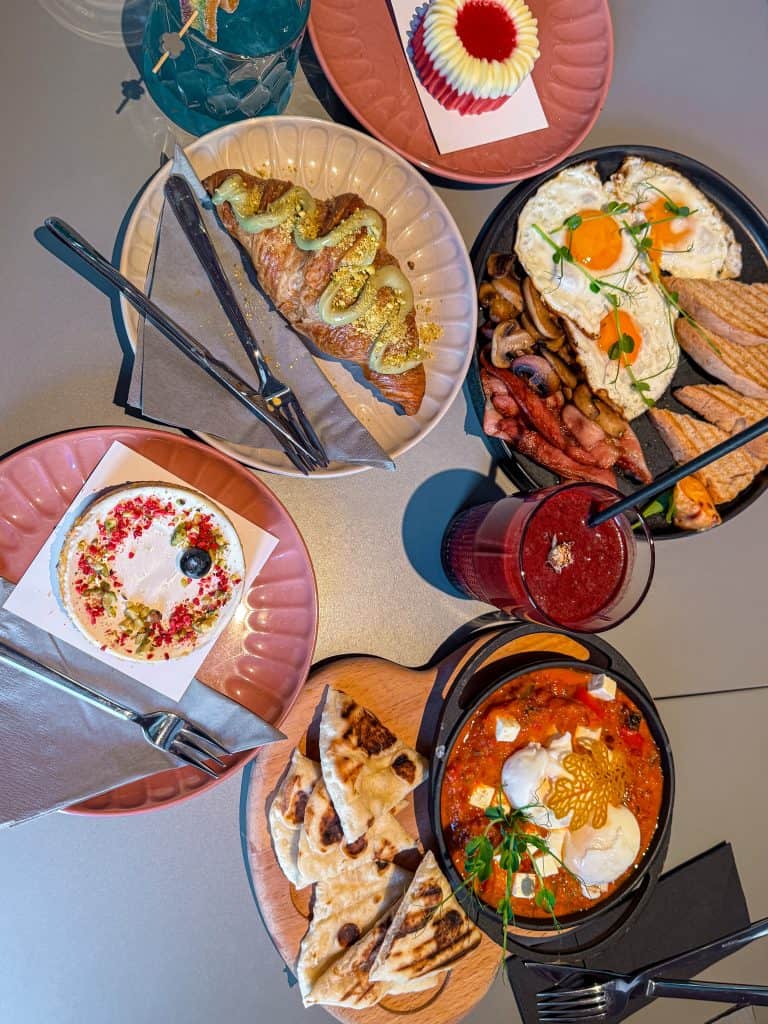 Colorful breakfast spread including eggs, pastries, fresh bread, fruit-topped dessert, and drinks, highlighting varied breakfast options, presentation, and vibrant colors for a delicious morning meal.