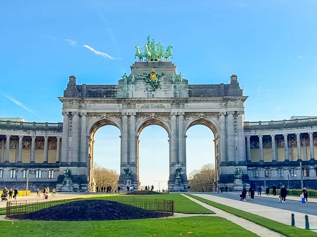 Elegant view of the historic Arc de Triomphe in Brussels, Belgium, showcasing its grand architecture, sculptures, and surrounding park with visitors enjoying the scenic outdoor landmark.