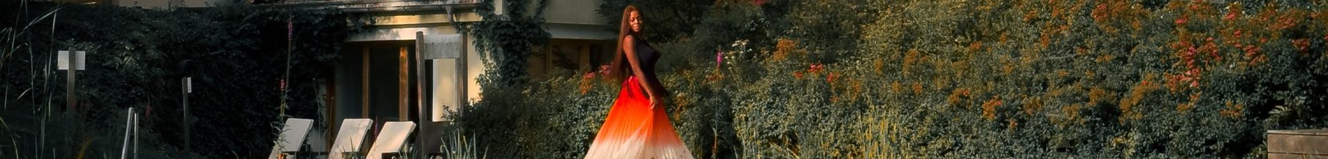 Twirling at the edge of a pond with a hotel in the background.