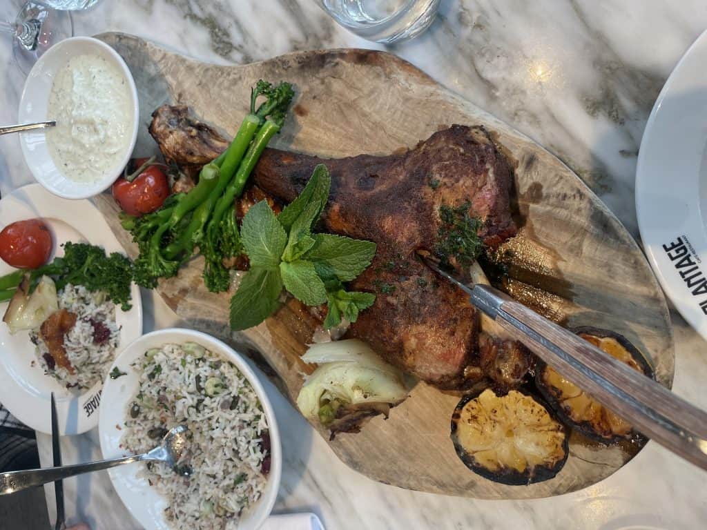 Juicy roasted lamb shank garnished with fresh herbs, accompanied by vegetables and sauces, showcasing a flavorful dish enjoyed in Amsterdam amidst the vibrant tulip season.