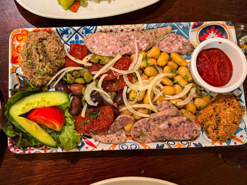 Authentic Mediterranean mezze platter featuring fresh vegetables, assorted meats, chickpeas, and flavorful dips, perfect for sharing and enjoying a variety of tastes.