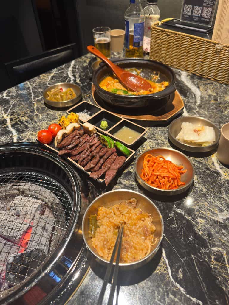 A traditional Korean BBQ meal with grilled beef, side dishes, and dipping sauces on a marble table.