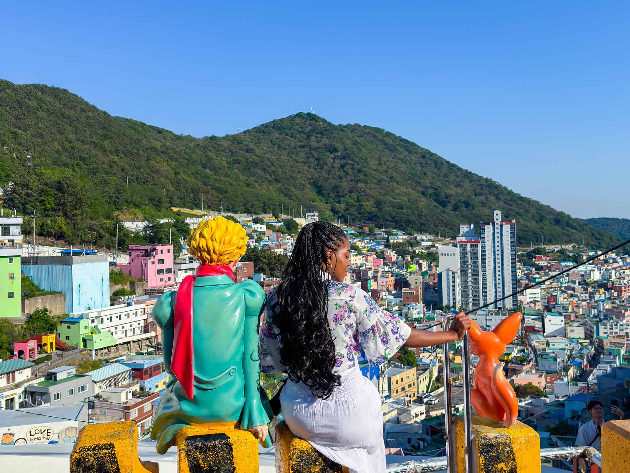 Nma Okafor enjoying the view of a colorful cityscape in South Korea with mountains in the background.